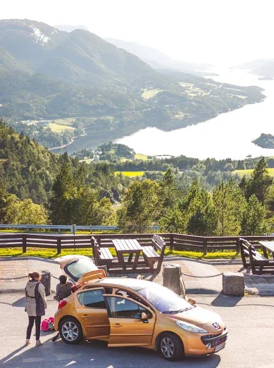 osoby stojí u oranžového auta s otevřeným kufrem