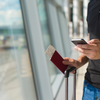 Muž s letenkami, pasem a mobilním telefonem na letišti